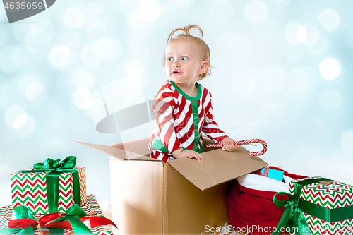 Image of Cute baby girl 1 year old sitting at box over Christmas background. Holiday season.