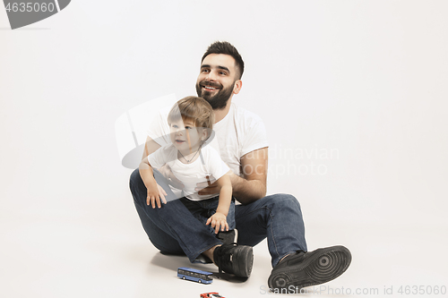 Image of happy family with kid sitting together and smiling at camera isolated on white