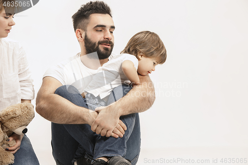 Image of happy family with kid sitting together and smiling at camera isolated on white