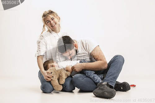 Image of happy family with kid sitting together and smiling at camera isolated on white