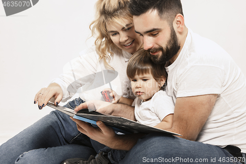 Image of happy family with kid sitting together and smiling at camera isolated on white