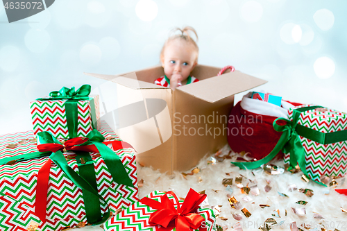 Image of Cute baby girl 1 year old sitting at box over Christmas background. Holiday season.