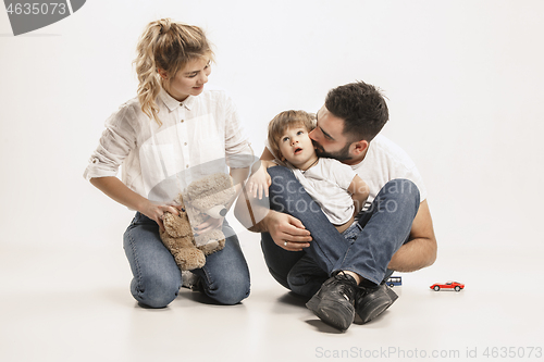Image of happy family with kid sitting together and smiling at camera isolated on white