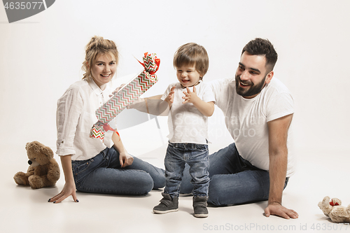 Image of happy family with kid sitting together and smiling at camera isolated on white