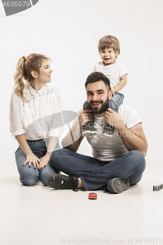 Image of happy family with kid sitting together and smiling at camera isolated on white