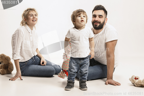 Image of happy family with kid sitting together and smiling at camera isolated on white