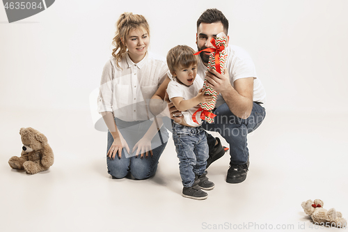 Image of happy family with kid sitting together and smiling at camera isolated on white