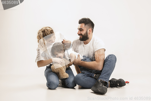 Image of happy family with kid sitting together and smiling at camera isolated on white