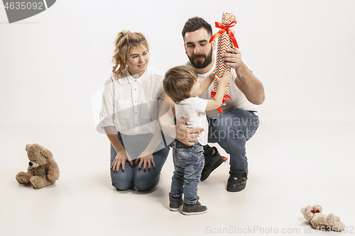 Image of happy family with kid sitting together and smiling at camera isolated on white