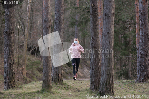 Image of Corona virus, or Covid-19, is spreading all over the world. Portrait of caucasian sporty woman wearing a medical protection face mask while running in nature.