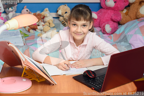 Image of A child learns at home at a desk with toys in the background