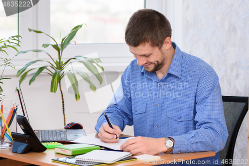 Image of Successful office employee adjusts the report while sitting at his workplace