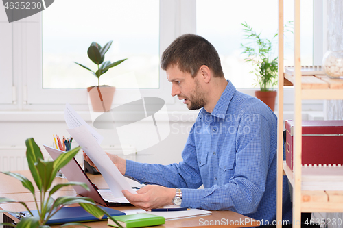 Image of An office employee is reading business papers in shock
