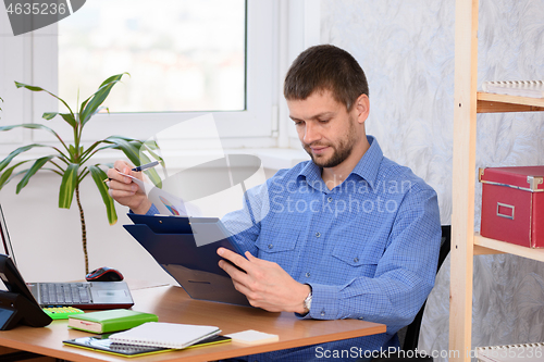 Image of Business man reads a printed report in a folder