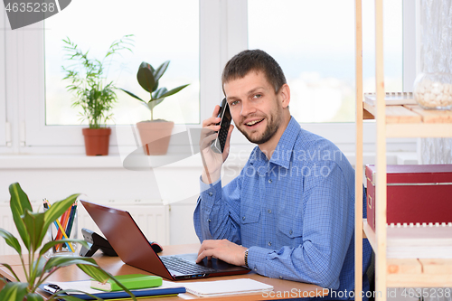 Image of Happy young man talking on the phone and looking in the frame