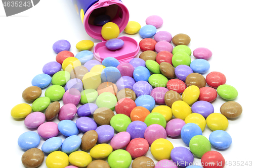 Image of Multicolored glazed chocolate candies out of the container 