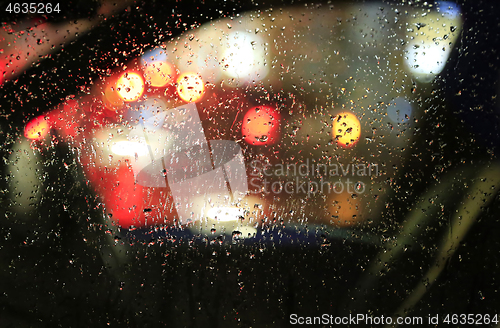 Image of Lights of night city through the glass of the car with raindrops