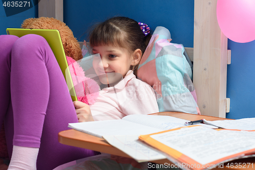 Image of Satisfied child relaxes with tablet in hand from lessons