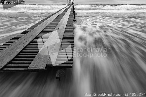 Image of Black and white photo - surf in the storm after sunset, pier, long exposure