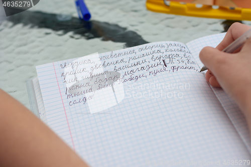 Image of The child learns to write letters correctly and writes various words in Russian in a notebook
