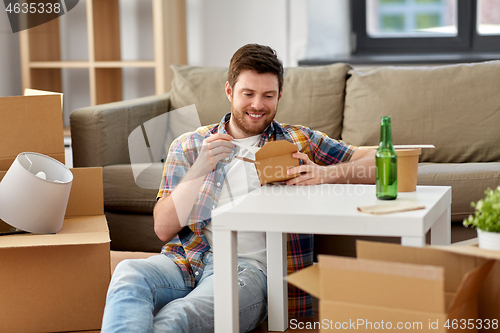 Image of smiling man eating takeaway food at new home