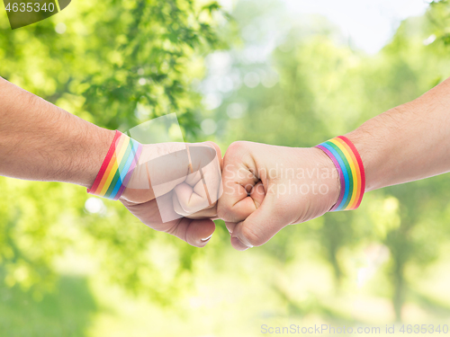 Image of hands with gay pride wristbands make fist bump