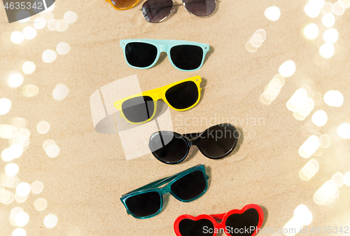 Image of different sunglasses on beach sand