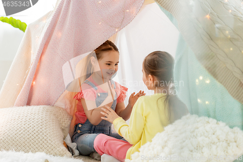 Image of girls playing clapping game in kids tent at home