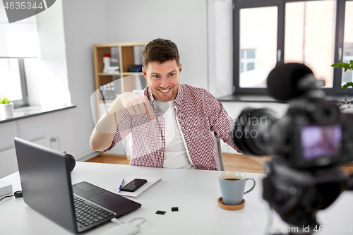 Image of male blogger with camera videoblogging at home