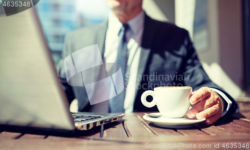 Image of senior businessman with laptop and coffee outdoors