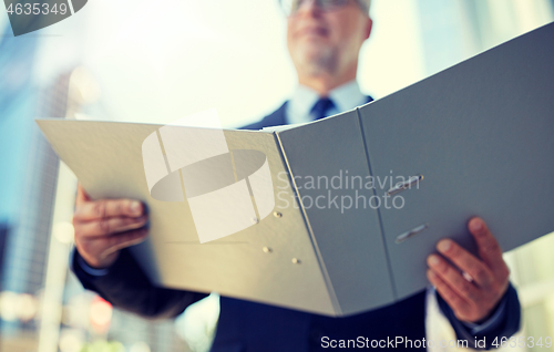 Image of senior businessman with ring binder folder in city