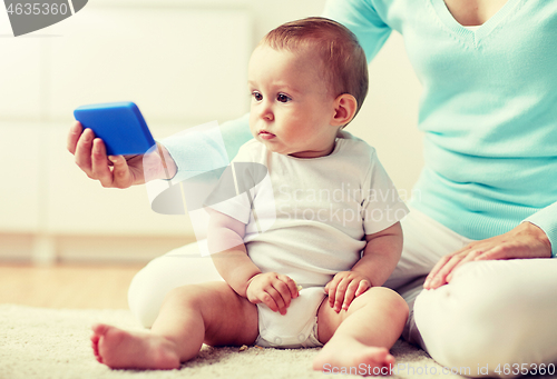Image of mother showing smartphone to baby at home