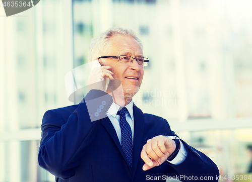 Image of senior businessman calling on smartphone in city