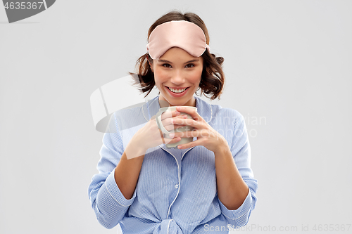 Image of woman in pajama and sleeping mask drinking coffee