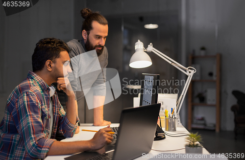 Image of creative team with computer working late at office