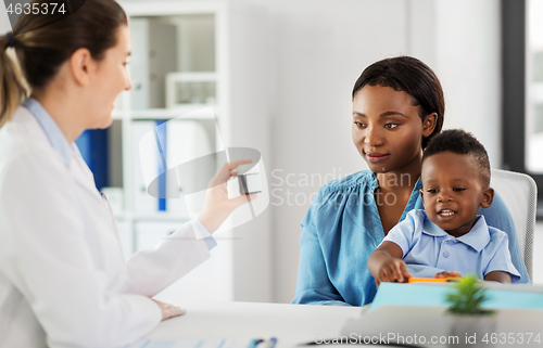 Image of doctor giving medicine to woman with son at clinic
