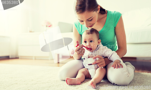 Image of mother with spoon feeding little baby at home