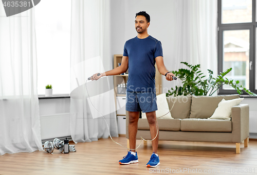 Image of indian man exercising with jump rope at home