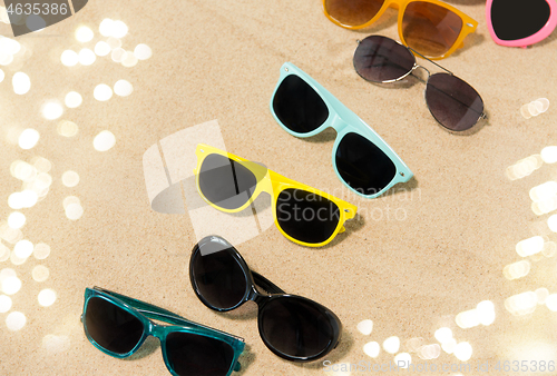 Image of different sunglasses on beach sand