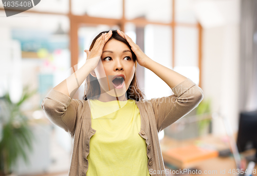 Image of stressed asian woman holding to her head at office