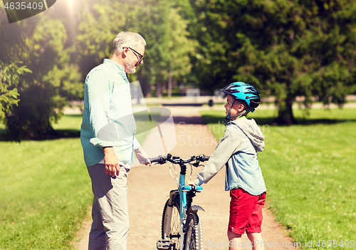 Image of grandfather and boy with bicycle at summer park