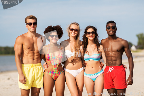 Image of happy friends hugging on summer beach