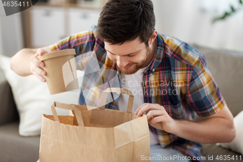 Image of smiling man unpacking takeaway food at home