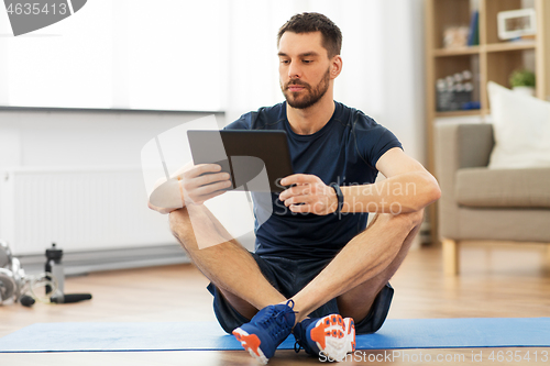 Image of man with tablet computer on exercise mat at home