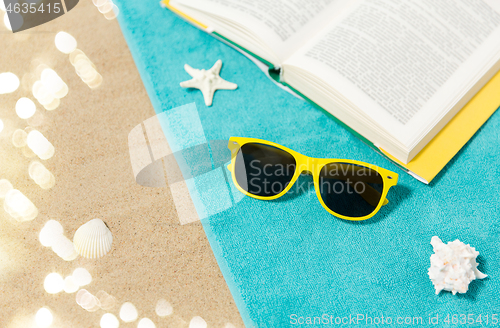 Image of sunglasses and book on beach towel on sand