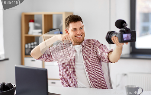 Image of male blogger with camera videoblogging at home