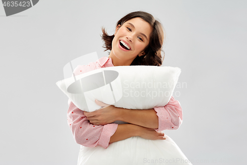 Image of happy young woman in pajama hugging pillow