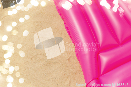 Image of pink swimming mattress on beach