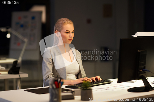 Image of businesswoman at computer working at night office