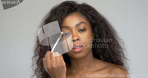 Image of Attractive ethnic lady applying makeup